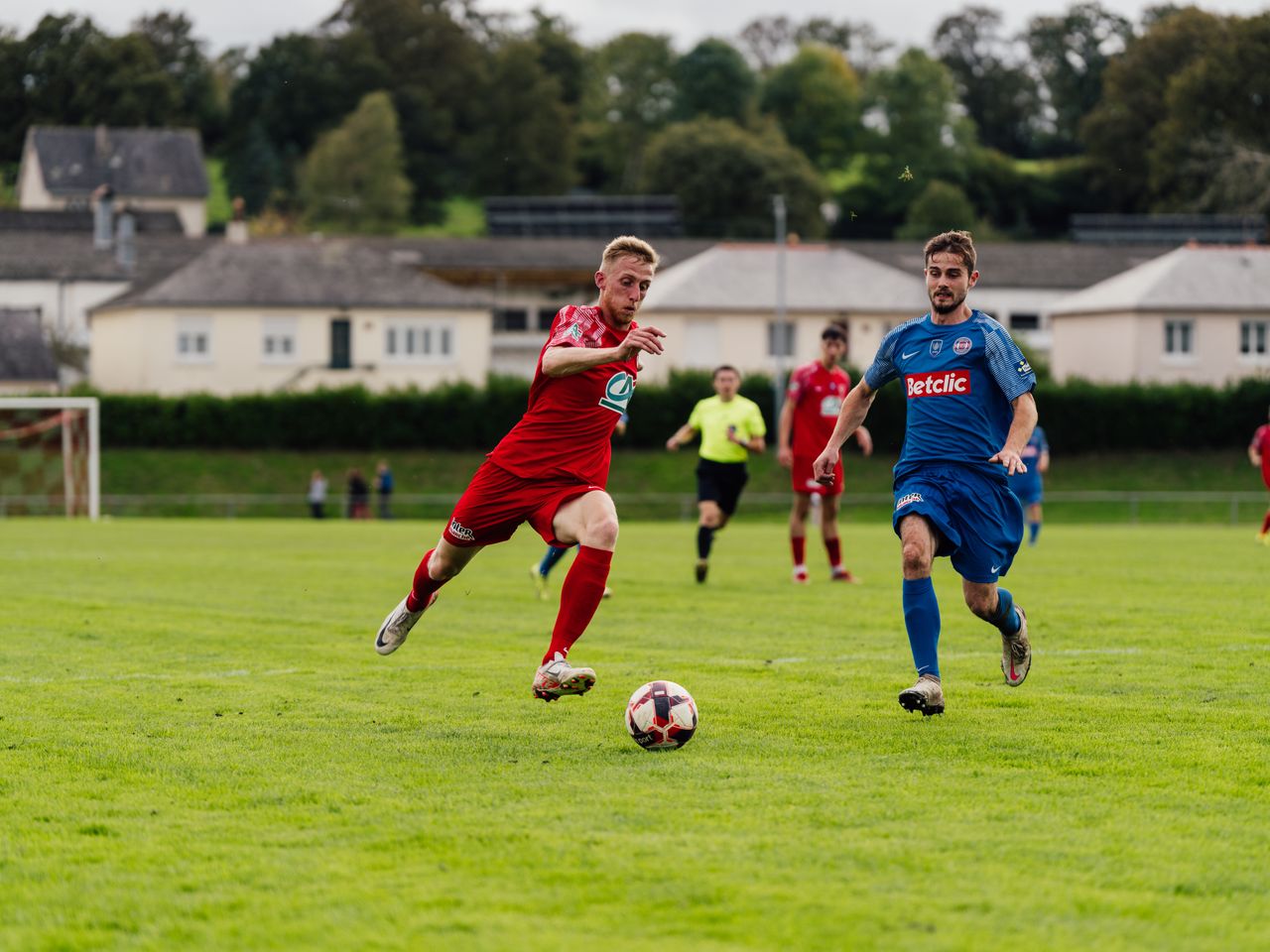 hero-02 Action shot of soccer players competing on a lush green field outdoors.