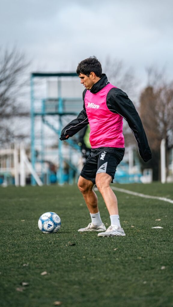 Soccer player in pink bib training on a field, capturing dynamic practice moment.
