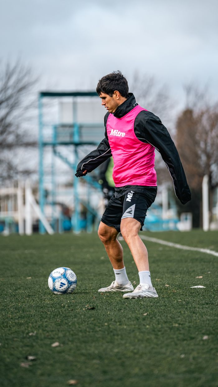 Soccer player in pink bib training on a field, capturing dynamic practice moment.