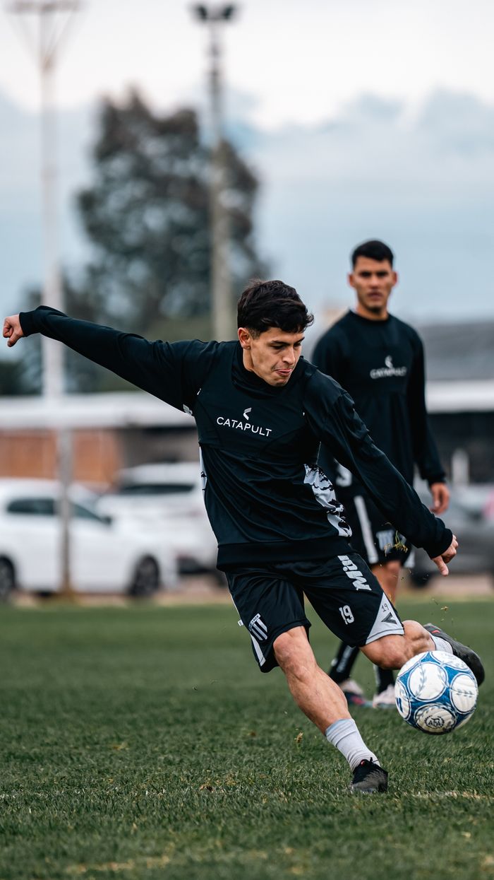 Dynamic shot of a soccer player kicking the ball during practice on a green field.